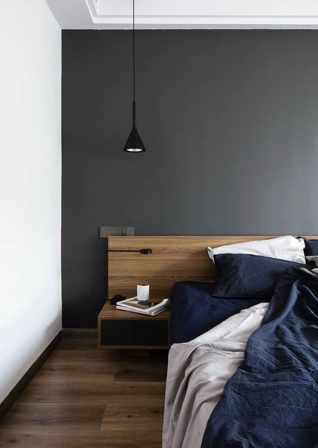 主卧室的床头背景墙刷成了深灰色,结合白色的墙面,吊顶和深蓝色的床品