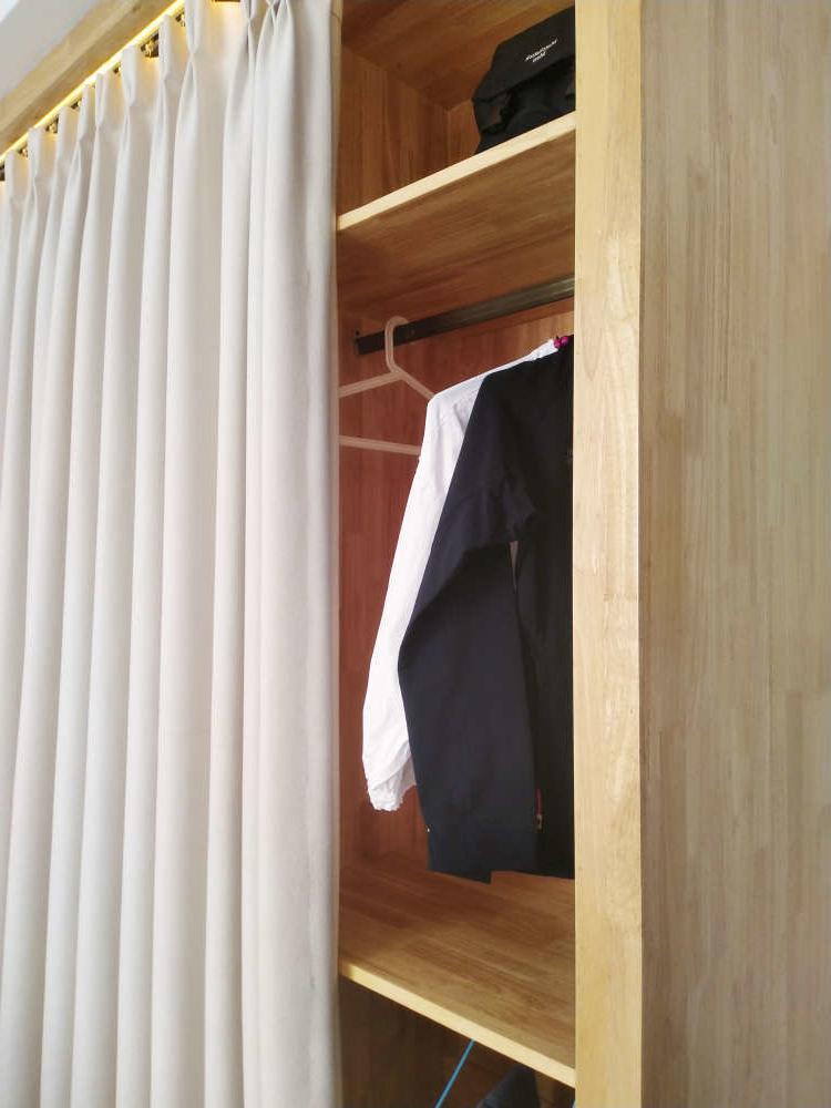 大衣柜没有安装柜门取而代之的是暖色的布帘,布帘相对柜门来说使用