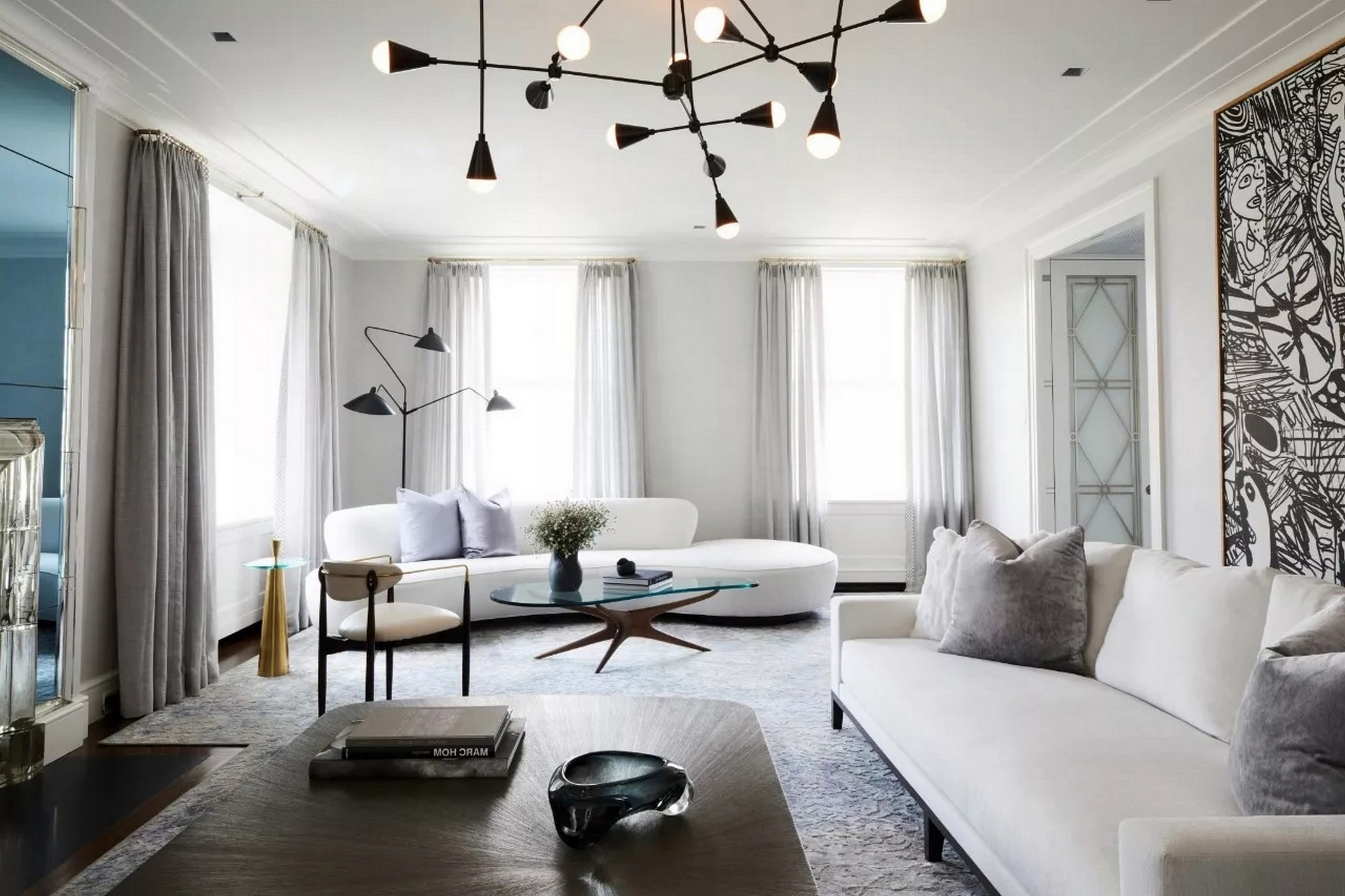 客厅的两个白色的布艺沙发,几个大大的落地窗,错落有致的灯具,茶几等