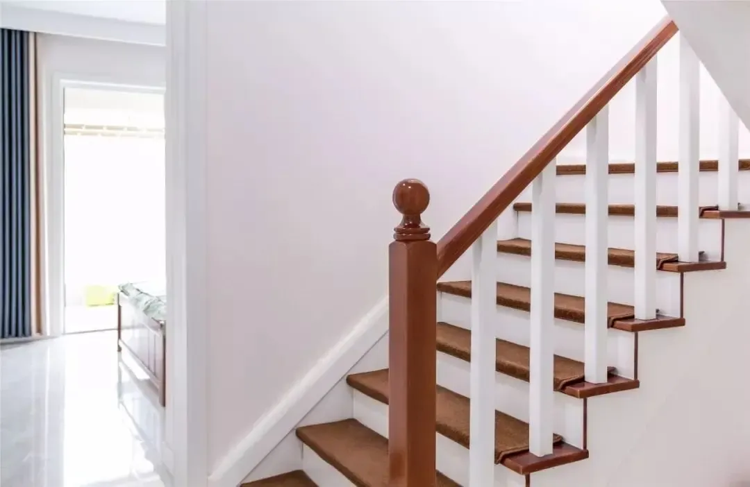 木色扶手与踏步的楼梯,在淡粉色的墙面下,显得舒适温馨而浪漫精致.